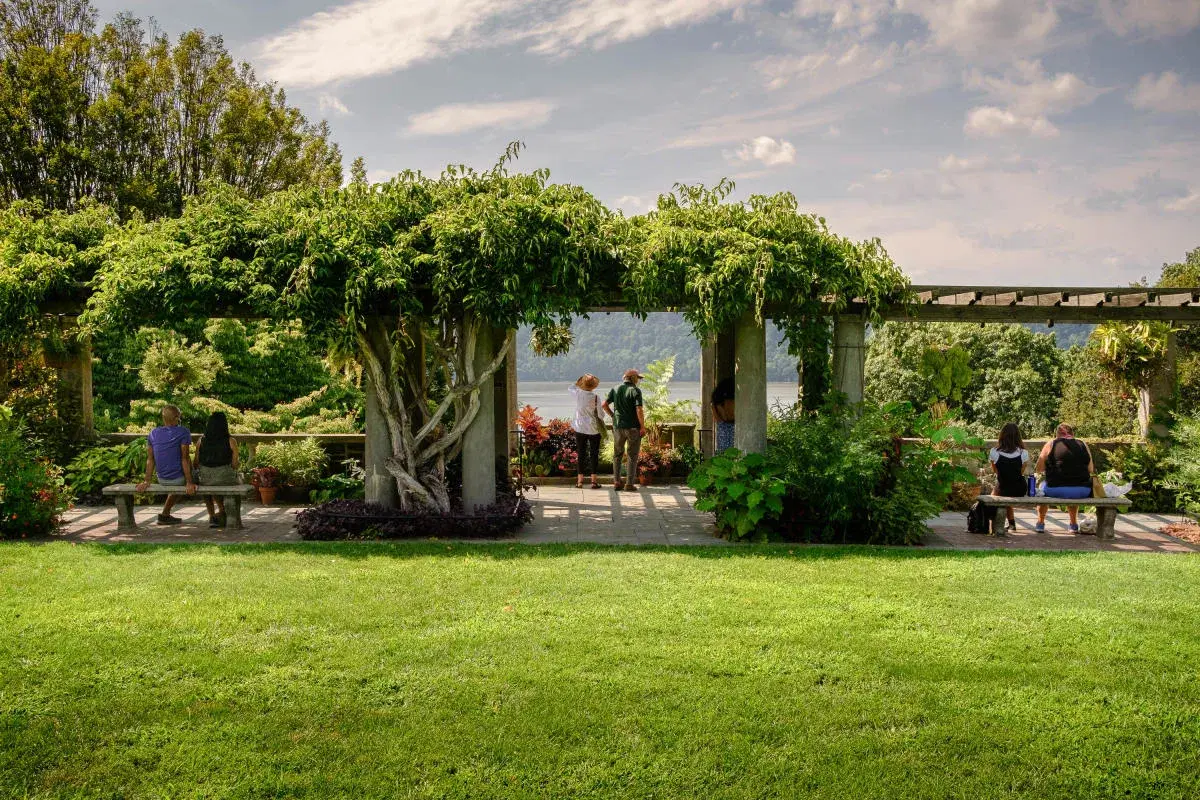 Pergola framing the views of the Hudson River, surrounded by colorful plantings, at Wave Hill Public Garden & Cultural Center, in The Bronx