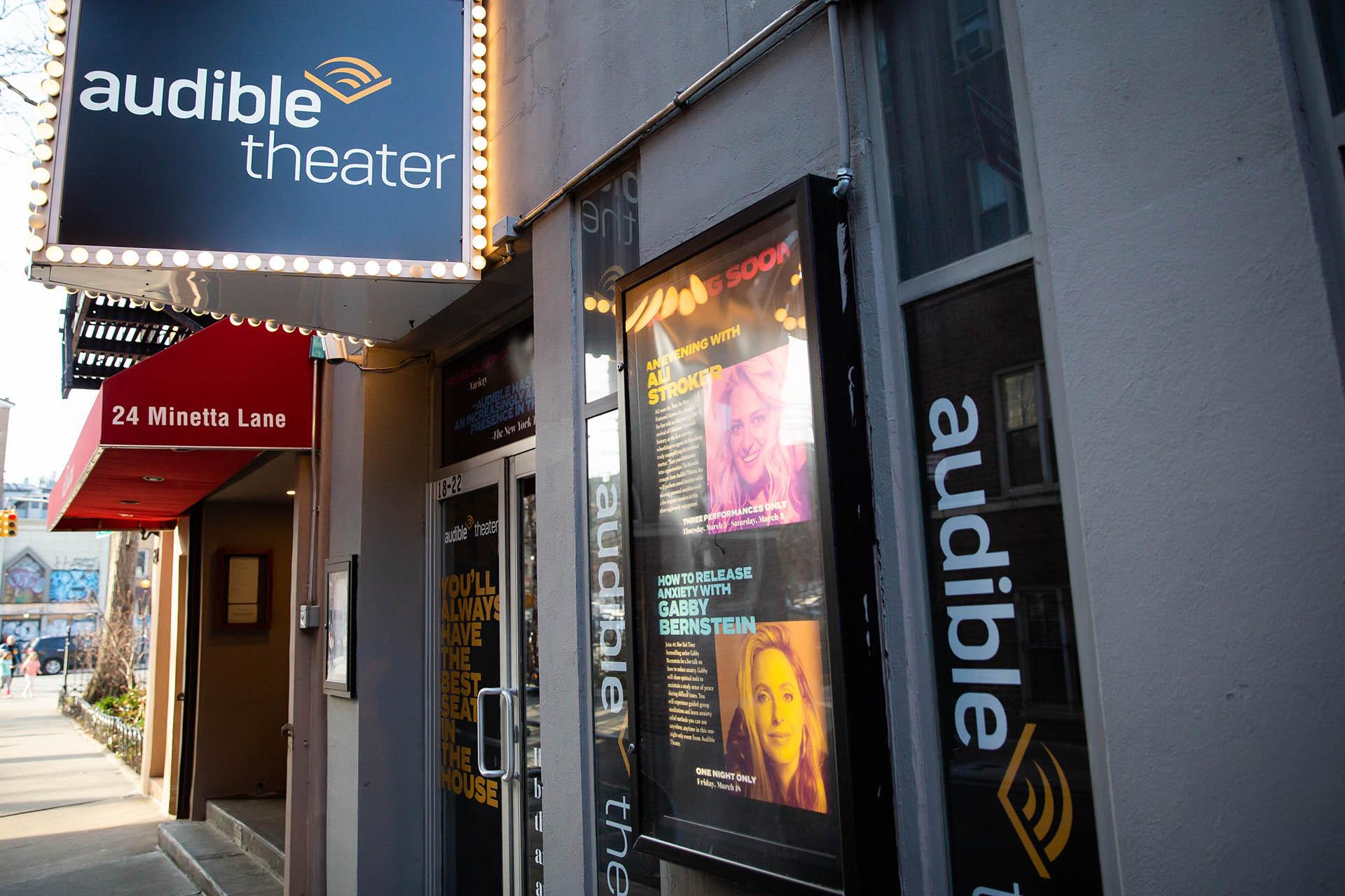The exterior of Audible Theater on a city street, with a marquee, posters advertising shows, and the address “24 Minetta Lane” visible next to the entrance.